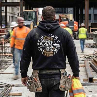 Person wearing a black hoodie with a skull design and text at a construction site.